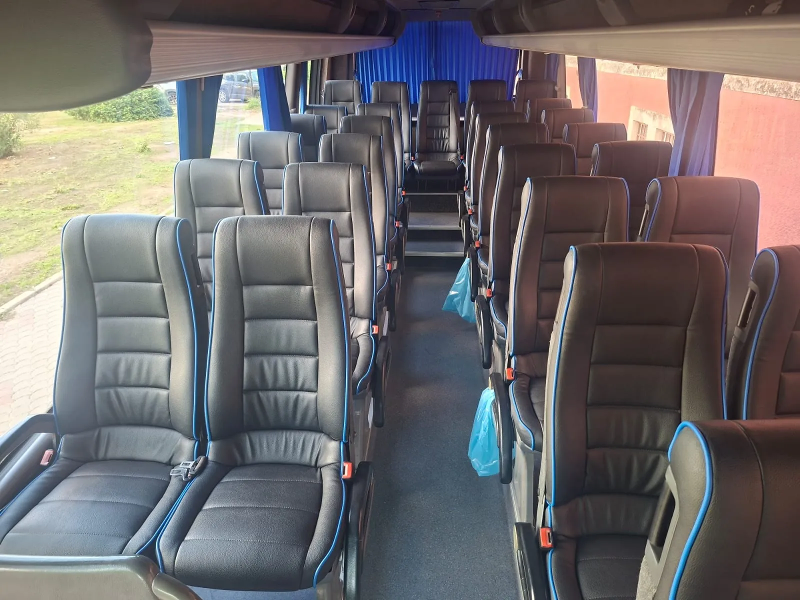 Interno del midibus con sedili in pelle e tende blu